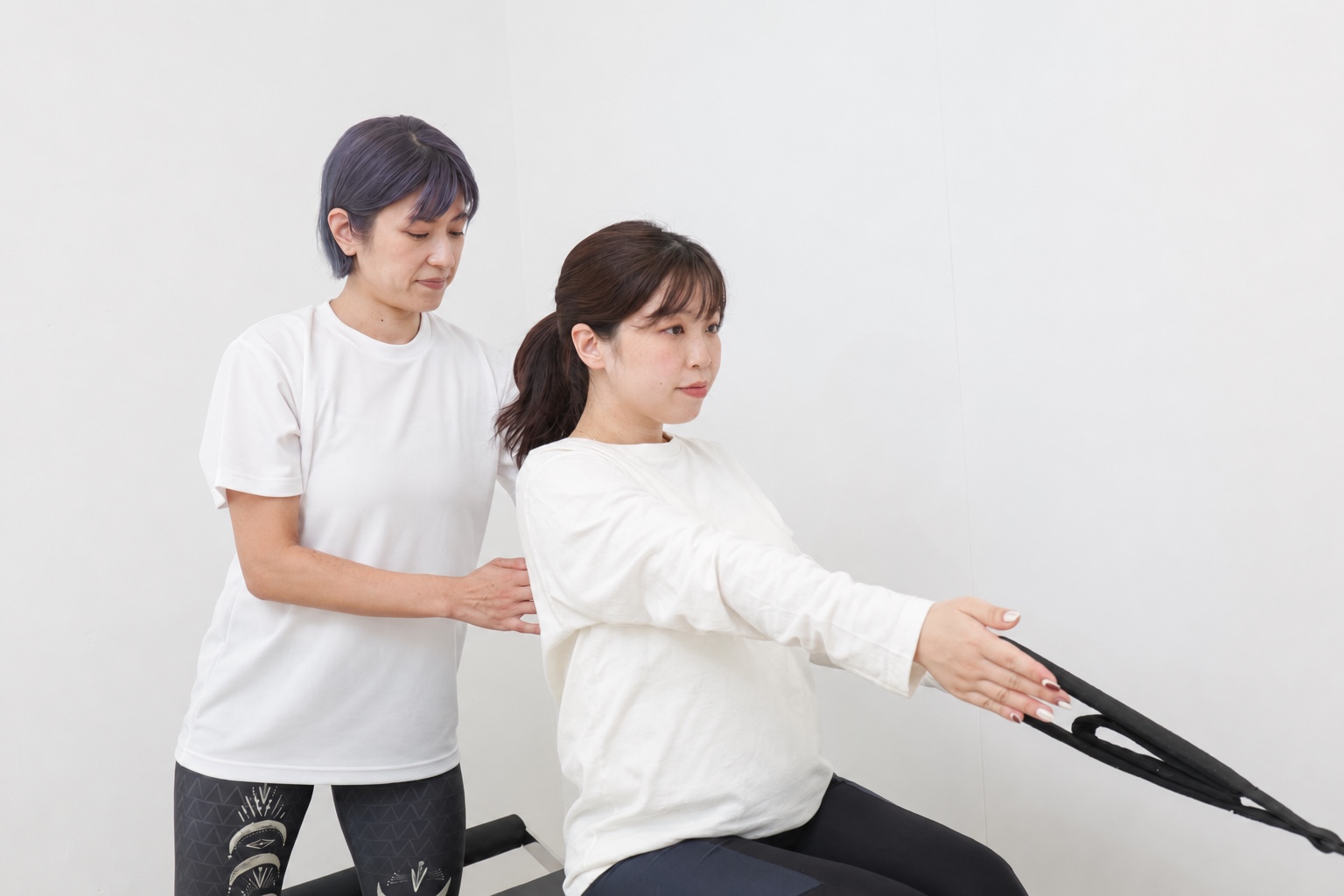 インストラクターが妊婦さんの姿勢を確認しながらピラティスを行う様子